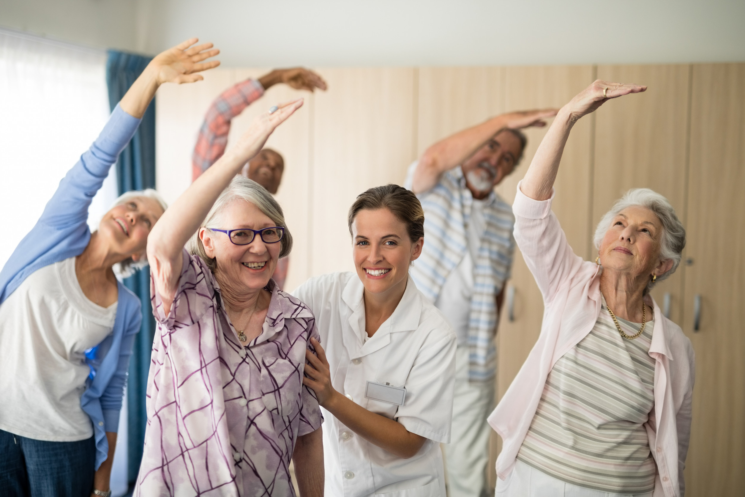 Portrait of smiling female doctor assisting senior woman exercising