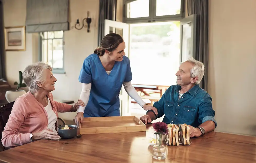 Shot of a young nurse checking up on a senior couple during breakfast at a nursing home